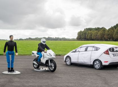 An AB Dynamics testing dummy, a testing dummy riding a motorbike, and a dummy car on a testing track