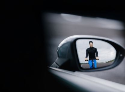 The wing mirror of a car angled to show an AB Dynamics test dummy riding a bicycle