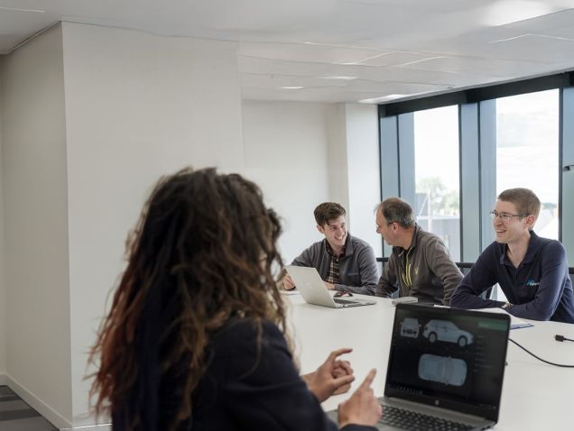 Five AB Dynamics colleagues laughing in a meeting room